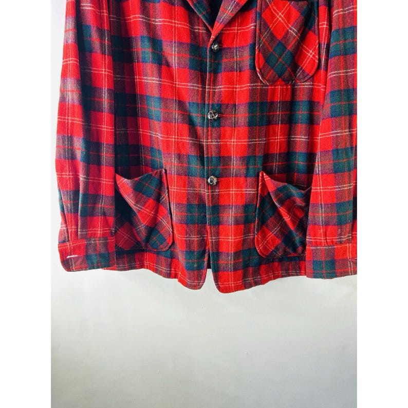 May include: A red and green plaid flannel shirt with a button-up front and two patch pockets.