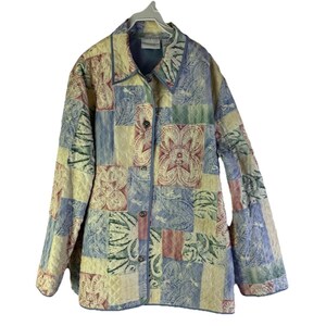 May include: A quilted jacket with a patchwork design in pastel colors. The jacket features a button-up front, long sleeves, and a collar. The patchwork includes floral and leaf patterns in shades of blue, green, pink, and yellow.