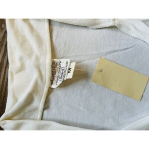 May include: White cotton t-shirt with a tag that reads "100% Combed Cotton, Machine Wash Warm, No Bleach Tumble Dry, Perma Prest, Sears, At Keep Trim Size, M".
