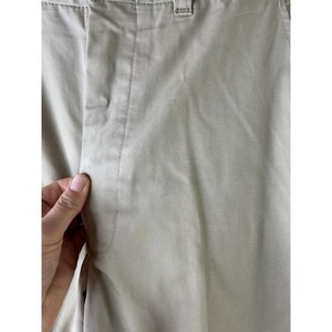 May include: A pair of beige cotton trousers with a straight leg and a centre crease.