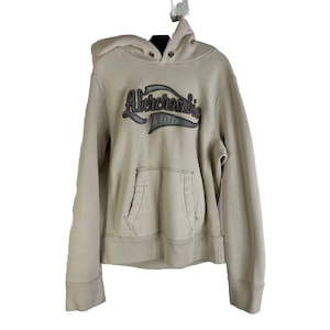 May include: A beige hooded sweatshirt with the text "Abercrombie & Fitch" in black and gray lettering on the front.