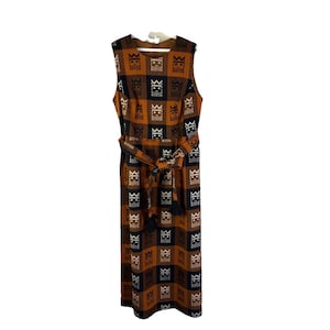 May include: A sleeveless, knee-length dress with a brown, black, and white checkered pattern. The dress features a matching belt with a tassel detail. The pattern includes a repeating crown motif.