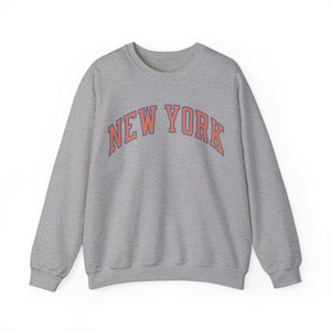 May include: A gray sweatshirt with the text "NEW YORK" in orange and blue letters.
