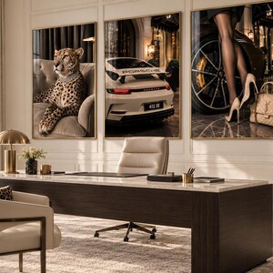 May include: A set of three framed wall art prints displayed above a desk. The left print shows a cheetah wearing a diamond necklace on a sofa. The center print features a white Porsche car. The right print depicts legs in stockings and heels.