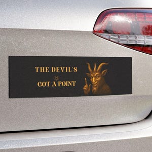 Peut inclure: Autocollant de pare-chocs rectangulaire noir avec texte doré et illustration dorée d'une chèvre. Le texte se lit "THE DEVIL'S GOT A POINT". L'illustration de la chèvre lève le pouce.