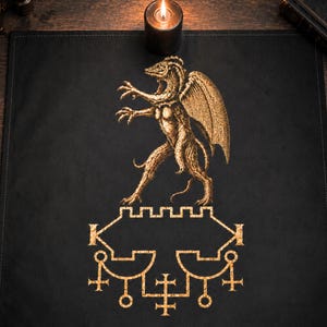 May include: A square black fabric altar cloth featuring a gold-coloured screen-printed design. The graphic depicts a winged dragon-like creature standing above a complex geometric sigil with cross-like symbols and lines in a metallic gold ink.