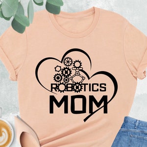 May include: A peach colored t-shirt with a black graphic of a heart with gears and the text "ROBOTICS MOM".