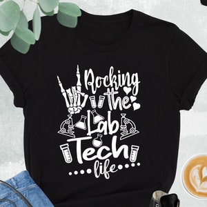 May include: Black t-shirt with a white graphic that says "Rocking the Lab Tech life..." with a skeleton hand making the rock and roll sign, a microscope, and test tubes.