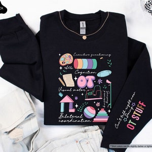 May include: Black sweatshirt with a colorful graphic design featuring the word "OT" surrounded by illustrations of various occupational therapy tools and activities. The text "Can't talk right now OT STUFF" is printed on the sleeve.