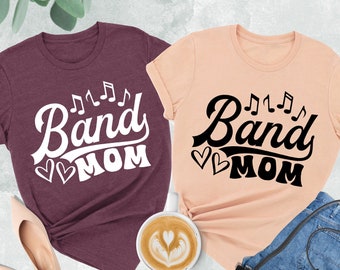 May include: Two t-shirts with the text "Band Mom" and musical notes. One shirt is heather maroon and the other is heather peach.