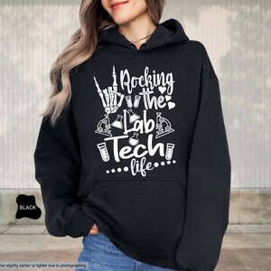 May include: Black hoodie with a white graphic that says "Rocking the Lab Tech life..." with a skeleton hand making a rock and roll sign, test tubes, and microscopes.