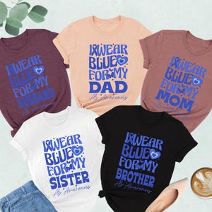 May include: Five t-shirts in different colors with the text "I wear blue for my [family member]" and a blue heart. The text "Alz Awareness" is also on each shirt. The family members are: Husband, Dad, Mom, Sister, Brother.