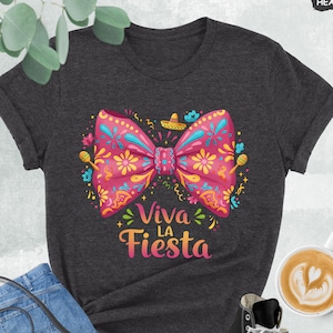 Może przedstawiać: Szary t-shirt w kolorze melanżu z ciemnym odcieniem, z r&oacute;żową i ż&oacute;łtą kokardą z kwiatowymi wzorami i napisem "Viva La Fiesta".