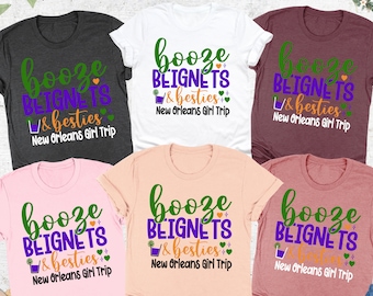 May include: Six t-shirts in different colours with the text "booze beignets & besties New Orleans Girl Trip" printed on them. The text is in green, purple, and white.