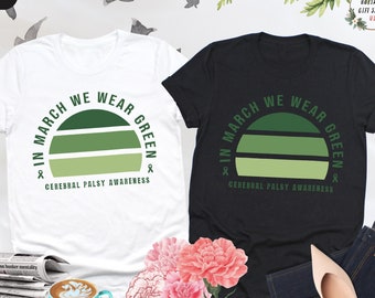 May include: Two t-shirts, one white and one black, with a green sunset graphic and the text "In March We Wear Green & Cerebral Palsy Awareness".