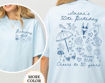 May include: Light blue t-shirt with a graphic on the front that says "Birthday Girl". The back of the shirt has a design with the text "Sarah's 30th Birthday Miami 2026 Cheers to 30 years". The shirt is a chambray color.