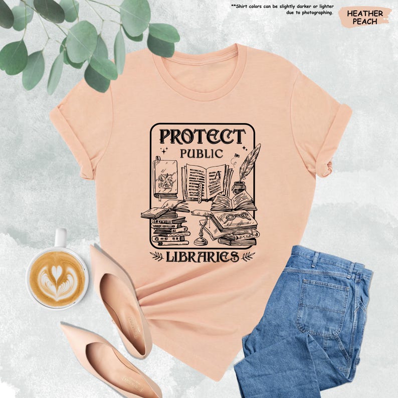 May include: A peach colored t-shirt with a black graphic design of a stack of books, a quill pen, and the text "Protect Public Libraries".