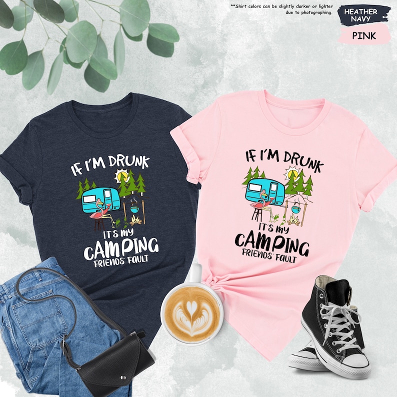 May include: Two t-shirts with a camping theme. The blue shirt says "If I'm Drunk It's My Camping Friends Fault". The pink shirt says "If I'm Drunk It's My Camping Friends Fault". Both shirts feature a cartoon camper, a flamingo, and a campfire.
