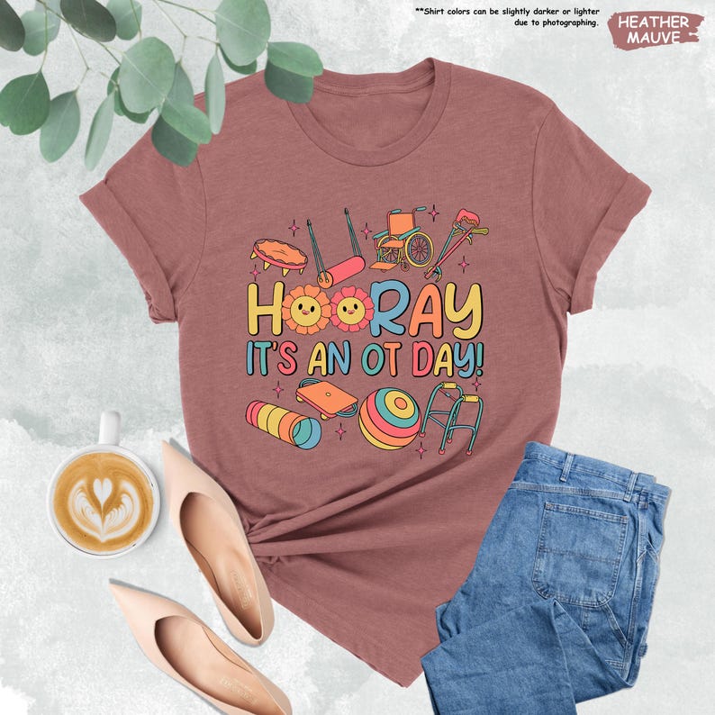 Peut inclure: T-shirt en mauve chin&eacute; avec un motif graphique d'outils d'ergoth&eacute;rapie et le texte "HOORAY IT'S AN OT DAY!"