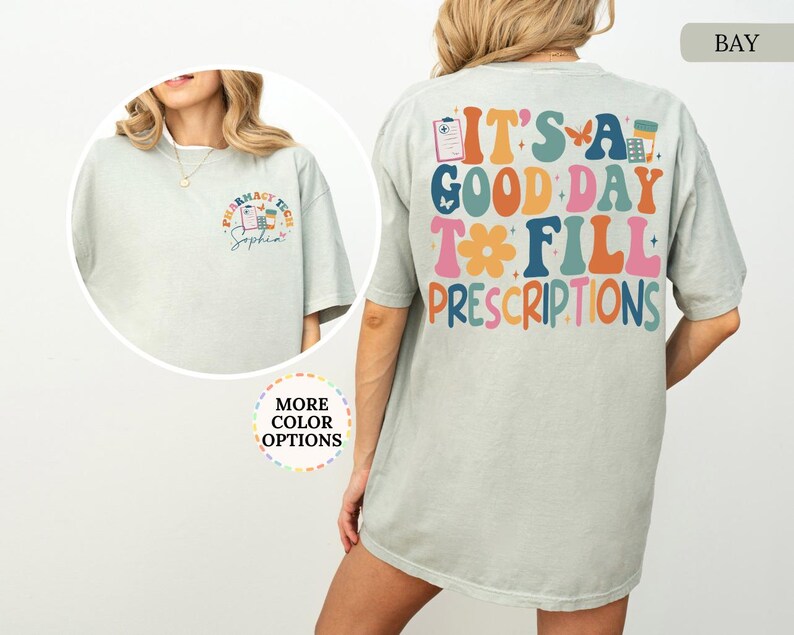 May include: A light green t-shirt with the text "IT'S A GOOD DAY TO FILL PRESCRIPTIONS" in colourful, retro-style lettering on the back. The front features a pharmacy tech design with the name "Sophia".