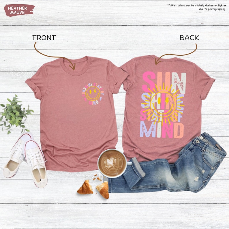Pu&ograve; includere: T-shirt color malva erica con disegni fronte e retro. La parte anteriore presenta una faccia sorridente con la scritta "Sunshine State of Mind". Il retro della maglietta riporta le parole "Sunshine State of Mind" in un design colorato. Le magliette sono abbinate a jeans e scarpe da ginnastica.