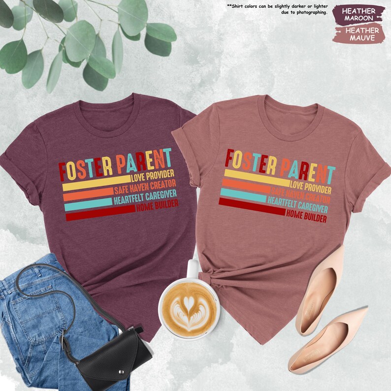 May include: Two heather colored t-shirts with the text "Foster Parent" in white and a colorful stripe design. The text below the stripes reads "Love Provider, Safe Haven Creator, Heartfelt Caregiver, Home Builder".