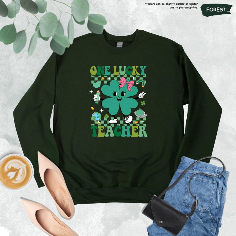 May include: Green sweatshirt with a four-leaf clover graphic and the text "ONE LUCKY TEACHER" in a retro style.