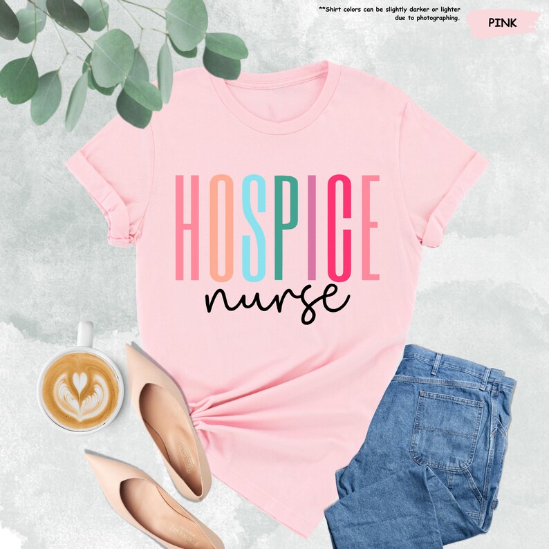 K&ouml;nnte beinhalten: Pinkes T-Shirt mit dem Text "HOSPICE nurse" in Regenbogenfarben. Der Text ist vertikal &uuml;bereinander angeordnet.
