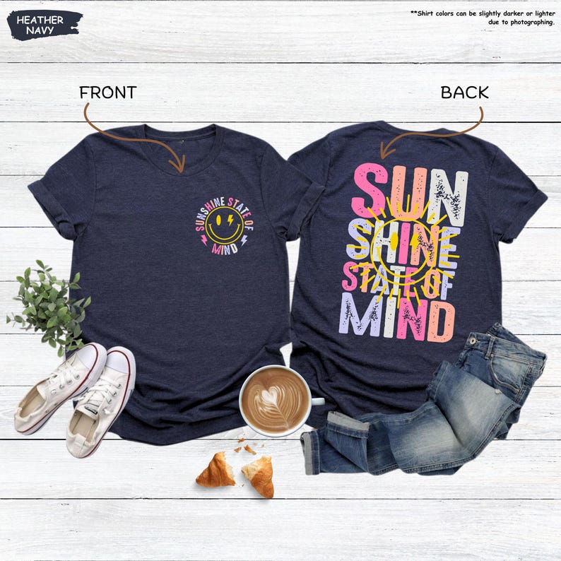 Pu&ograve; includere: T-shirt blu navy melange con la scritta "Sunshine State of Mind" e una grafica con faccina sorridente sul davanti. Il retro della maglietta presenta le parole "Sun Shine State of Mind" in un design colorato. Le magliette sono abbinate a jeans e scarpe da ginnastica.