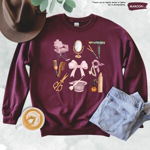 a maroon sweater with a bow, scissors, and other items on it