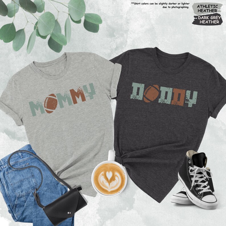 May include: Two t-shirts with a distressed vintage look. The grey shirt says "MOMMY" with a football graphic. The dark grey shirt says "DADDY" with a football graphic.