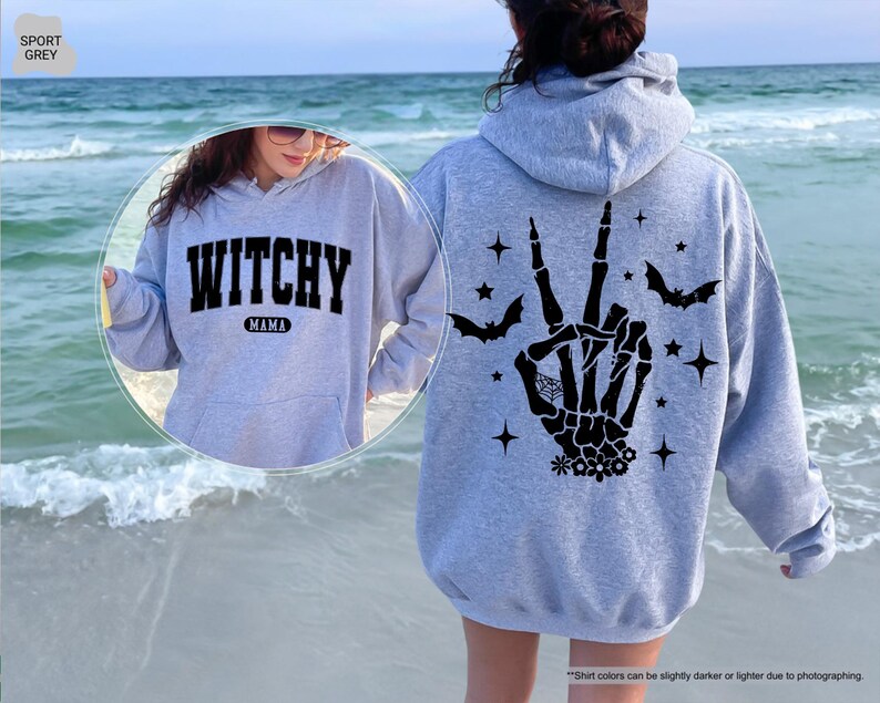 a woman wearing a witches hand hoodie on the beach