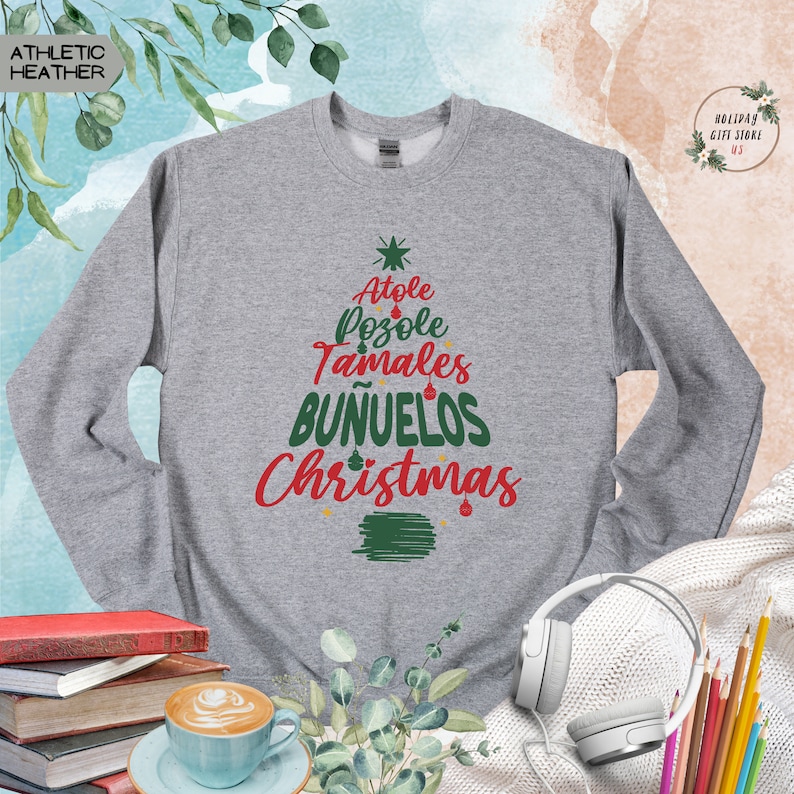 May include: Gray sweatshirt with a green Christmas tree design. The tree is made up of the words "Atole", "Pozole", "Tamales", "Bunuelos", and "Christmas".