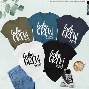 May include: Five t-shirts in different colors with the text "tube crew 2025" printed in white on each shirt. The shirts are laid out on a white surface with a cup of coffee and a pair of sneakers.