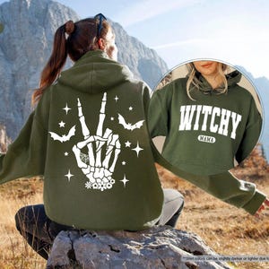 a woman sitting on a rock wearing a green witch hoodie