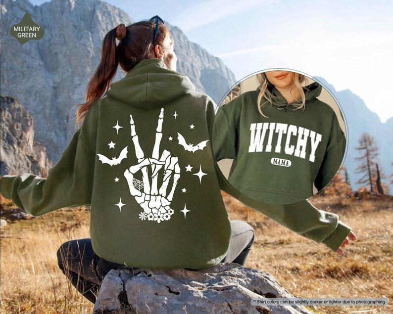 a woman sitting on a rock wearing a green witch hoodie