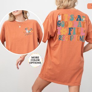 May include: A terracotta-coloured t-shirt featuring the text "IT'S A GOOD DAY TO FILL PRESCRIPTIONS" in various colours on the back. The front has a smaller design with prescription graphics and the name "Sophia".