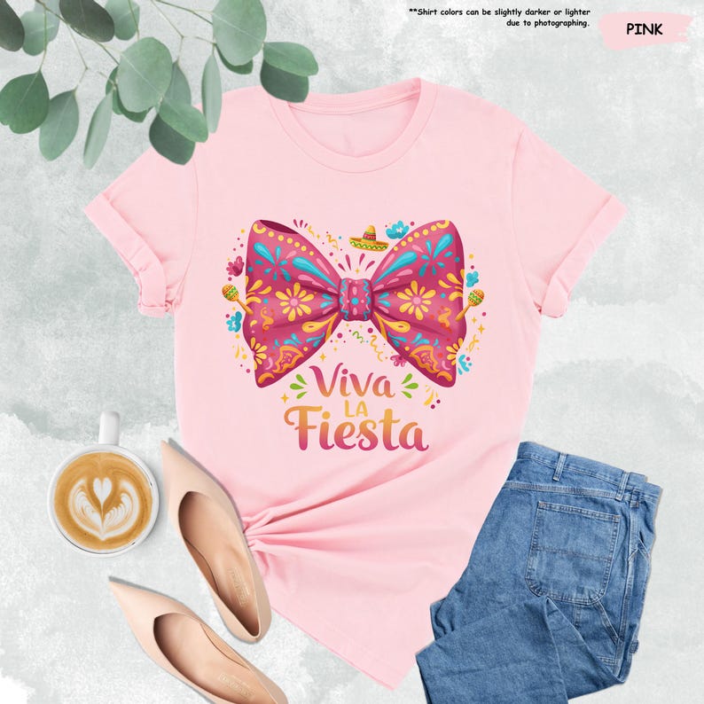 Może przedstawiać: R&oacute;żowa koszulka z kolorową kokardką i napisem "Viva la Fiesta".