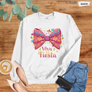Może przedstawiać: Biała bluza z r&oacute;żową kokardką w kwiatowy wz&oacute;r i napisem "Viva La Fiesta".