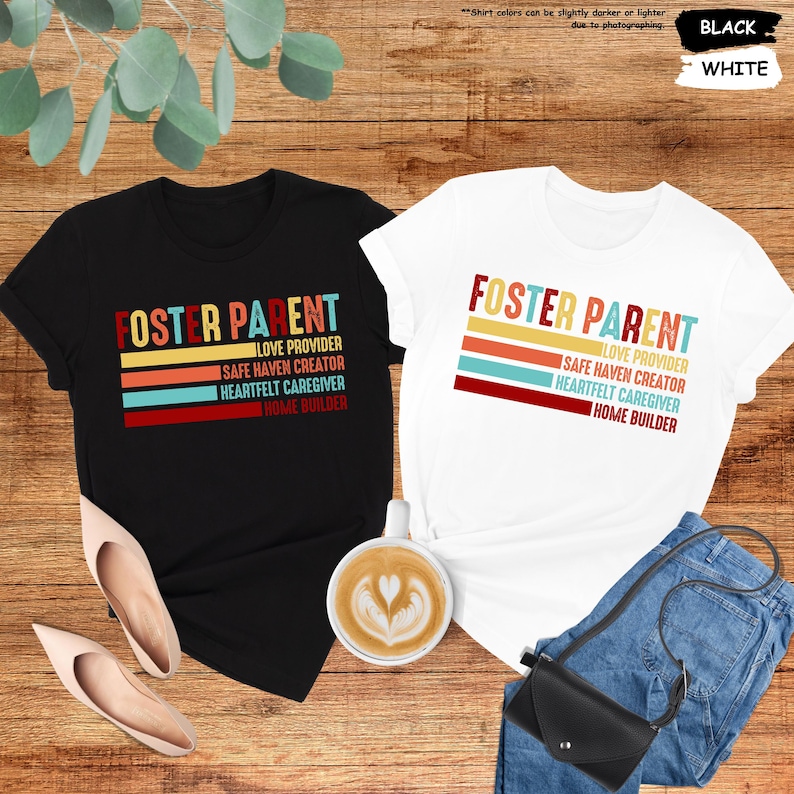 May include: Two t-shirts with the text "Foster Parent" in a retro font. The text is layered over a colorful striped design. The shirts are black and white.