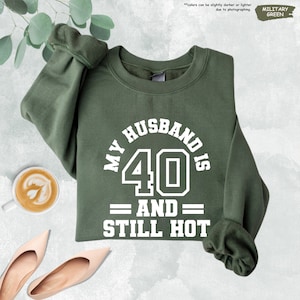 a green sweatshirt with the words, my husband is 40 and still hot