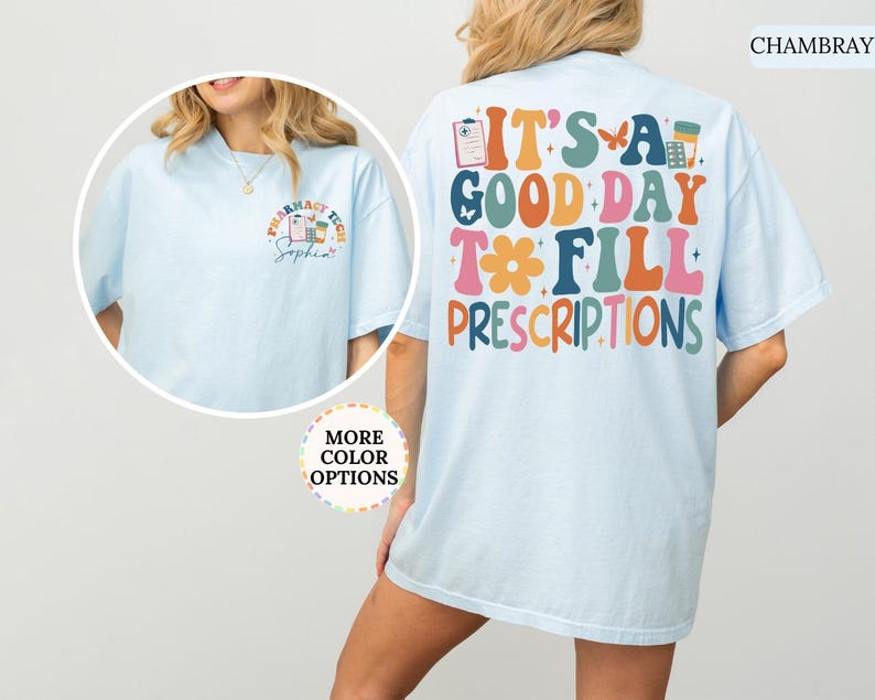 May include: Pale blue t-shirt featuring the phrase "IT'S A GOOD DAY TO FILL PRESCRIPTIONS" in various colours on the back. The front displays a smaller design with pharmacy-related graphics and the words "PHARMACY TECH".
