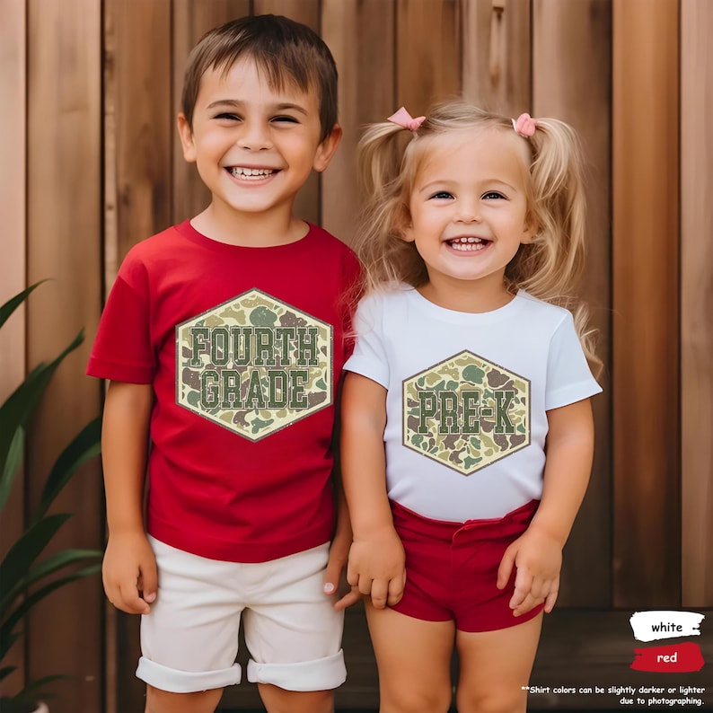 May include: Two children in red and white t-shirts with camouflage text. The red shirt displays "FOURTH GRADE" in a hexagon, and the white shirt says "PRE-K". Both shirts have short sleeves and are worn with shorts.