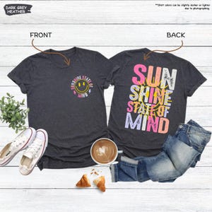 Pu&ograve; includere: T-shirt grigio scuro m&eacute;lange con la scritta "Sunshine State of Mind" e una grafica a faccina sorridente sul davanti. La parte posteriore della maglietta presenta le parole "Sun Shine State of Mind". Abbigliamento casual.