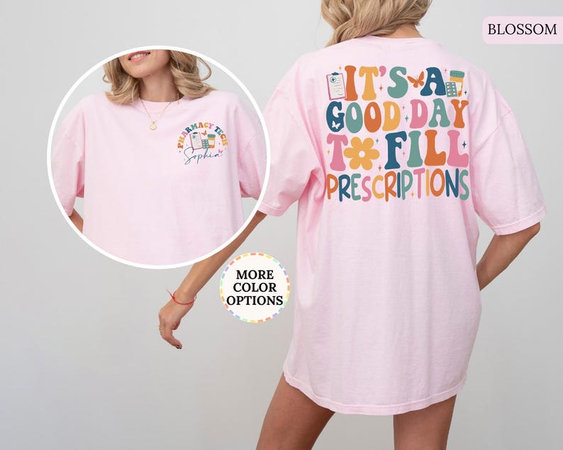 May include: A pale pink t-shirt featuring the phrase "IT'S A GOOD DAY TO FILL PRESCRIPTIONS" in vibrant colours on the back. The front displays a small graphic with "Pharmacy Tech" and a name. The t-shirt has a relaxed fit.