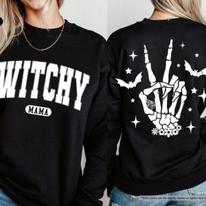 a woman wearing a black sweater with a hand print on it