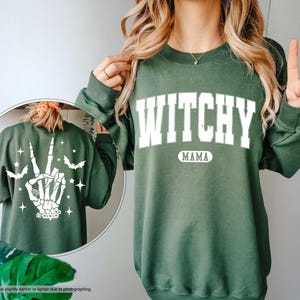 a woman wearing a green sweatshirt with the words witch on it