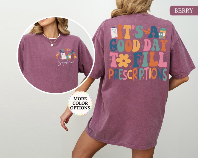 May include: Berry-coloured t-shirt with the text "It's a good day to fill prescriptions" on the back in colourful, retro-style lettering. The front features a smaller design with pharmacy-related graphics and the name "Sophia".