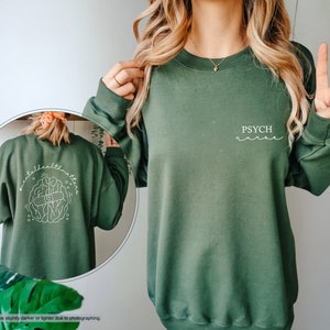 a woman wearing a green sweatshirt with a peace sign on it