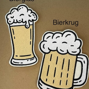 Può includere: Due toppe ricamate raffiguranti bicchieri da birra. Una toppa raffigura un bicchiere alto con schiuma, l'altra un boccale di birra con manico e schiuma. Le toppe hanno un riempimento giallo e contorni bianchi e neri. I testi 'Bierglas' e 'Bierkrug' sono visibili.